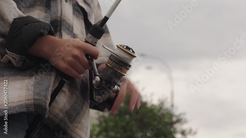 A little boy is fishing on a big river using a spinning rod