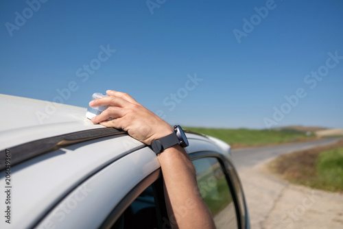 Photography Hand placing v16 emergency light beacon on car roof during roadside breakdown on