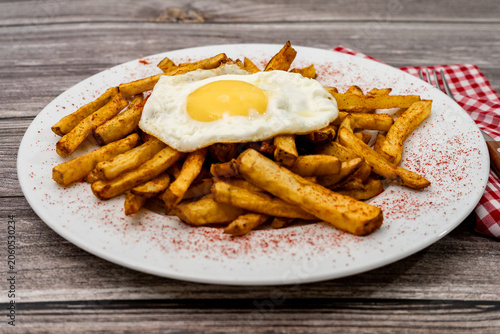 French fries with fried egg and paprika on plate