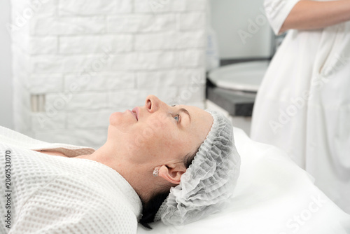 Photos Mature woman receiving facial treatment mask in spa beauty salon