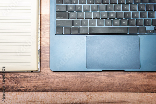 Top view of a laptop keyboard and a notebook with blank space.