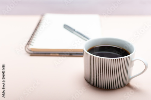 A close-up of a cup of coffee in front of a workspace.