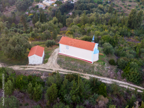 Rural chapel nestled amongst trees and a dirt road.