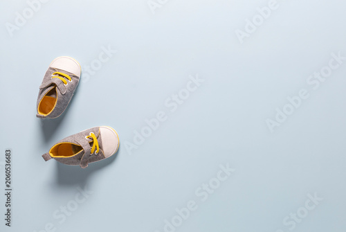 Baby booties, gray and yellow, on a blue background. Top view.