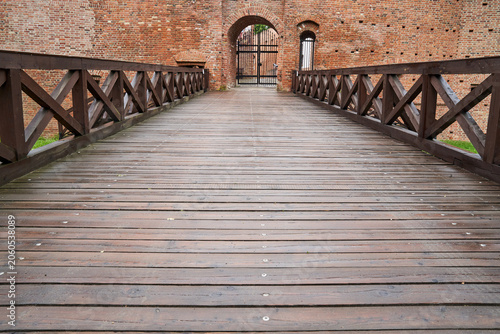 Wooden bridge over the moat, gate, and walls of the historic medieval castle in Miedzyrzecz