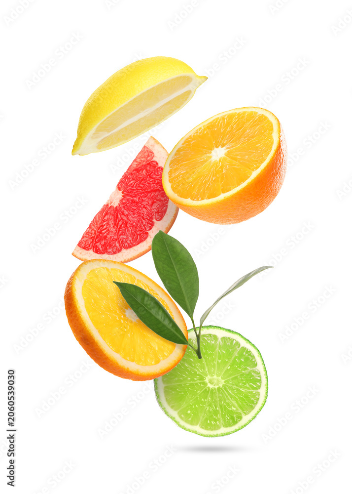 Obraz premium Different cut citrus fruits and green leaves falling on white background