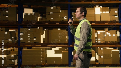 Bild auf Leinwand Man depot personnel coordinating cargo loading with walkie-talkie speaker communication, two-way radio technology improves teamwork