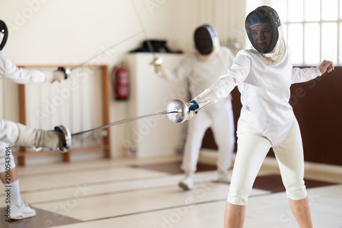 Obraz na plátne Man and woman in fencing kit engage in friendly sparring match, focusing on foot