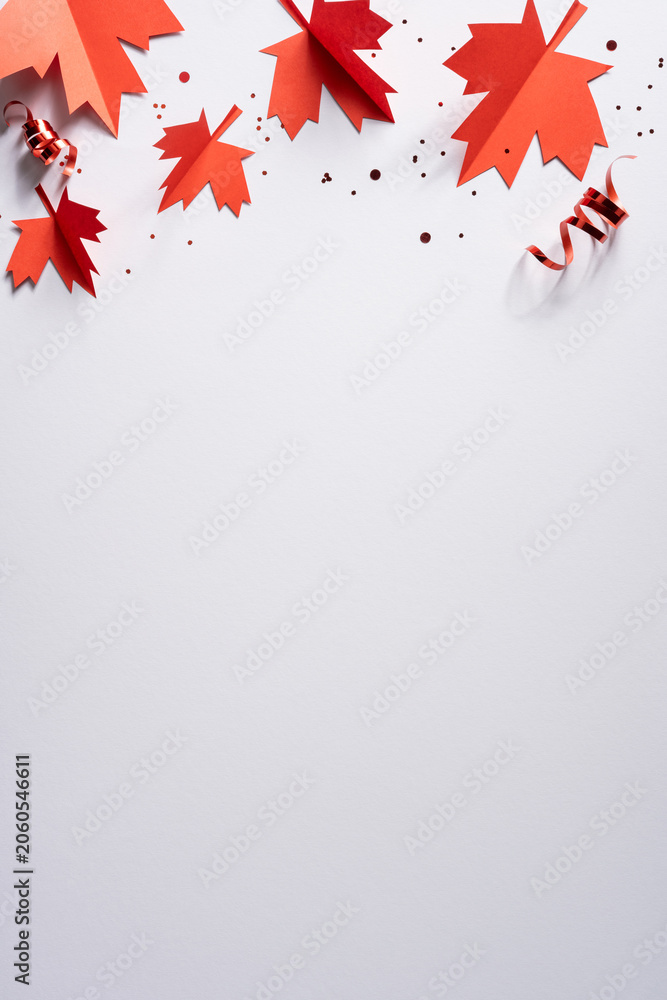 Obraz premium Red paper maple leaves and confetti for Canada Independence Day celebration with blank vertical space for text