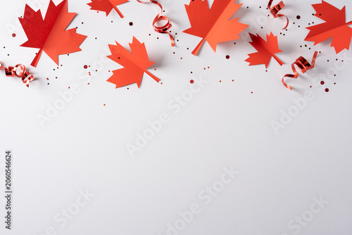 Red paper maple leaves and curled ribbons for Canada independence day celebration with confetti and blank space