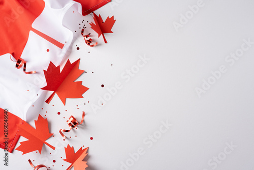 Canada Independence Day concept with flag, maple leaf cutouts and confetti on white background