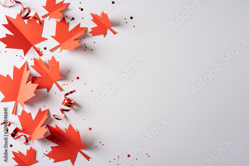 Red paper maple leaves and ribbons celebrating Canada Independence Day with confetti on white background
