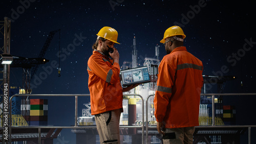 Obraz na plátne Offshore platform men use map on device to circumvent petrol extraction blockade, african american expert and drilling rig colleague search