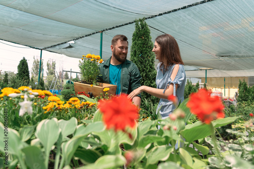 Bild auf Leinwand Worker helping female customer to buy flowers in garden center