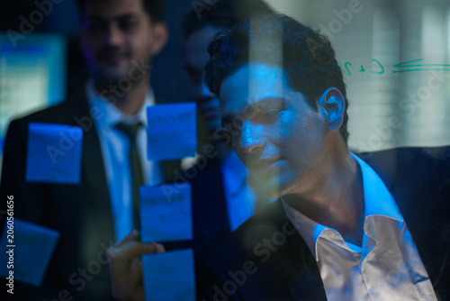 Professional team collaborating on a high-level strategic project, visualizing technical workflows and innovative task management on a glass board in a high-tech corporate office.