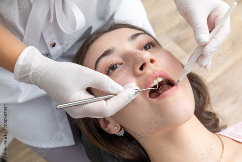 Dentist examining patient teeth with dental mirror during dental check up