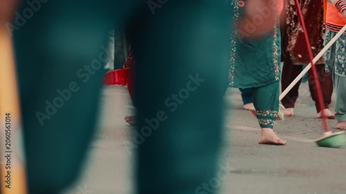 Crowd of Indian religious women clean the road for the Sikh guru