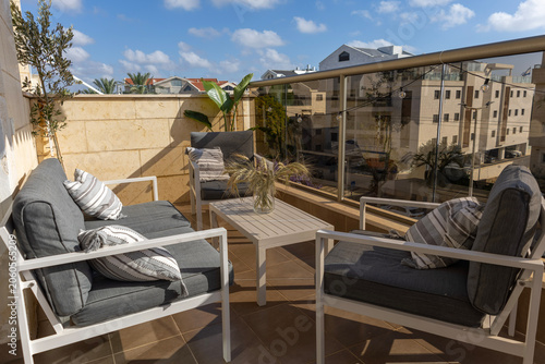Tableau sur toile Cozy and modern balcony lounge area with comfortable outdoor furniture, cushions, and decorative plants