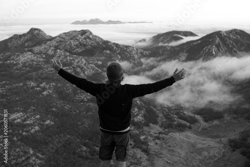 Person with Outstretched Arms Above Clouds in Mountain Landscape