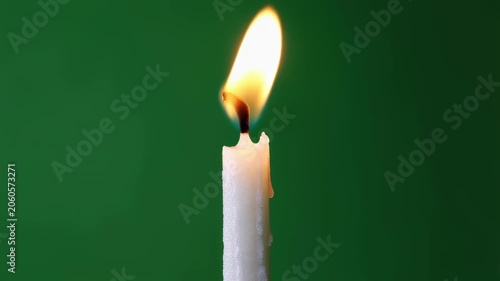 Elegant Christmas candle with realistic flickering flame on green background