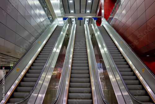 Symmetrical low-angle view of multiple modern escalators in a public transit station or shopping mall interior.