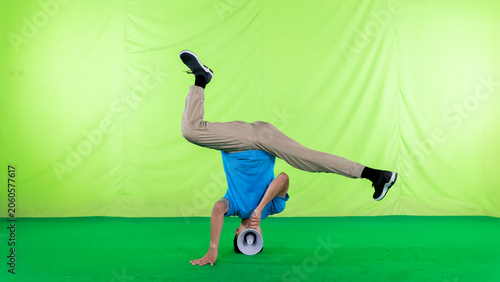 Fotografie Athletic Asian Male Dancer Performing Headstand Breakdance Move on Green Screen