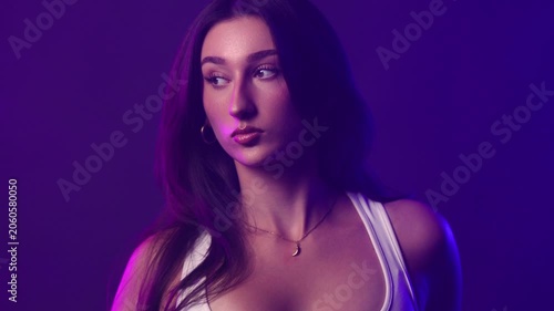 Fashion and beauty concept a young woman posing in a studio with dramatic neon lighting. The model style and glamour with purple and pink light illuminating her face and body. Commercial, editorial, a
