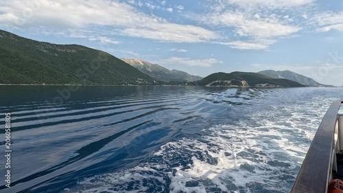 Close-up view of a passenger ferry moving through the Ionian Sea near the Greek islands. White water splashes and foamy waves flow alongside the vessel hull, creating a dynamic maritime travel and tra