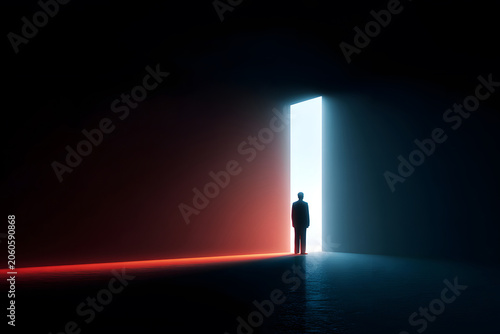 Person standing in front of a light-filled door in a dark space during a quiet moment in time