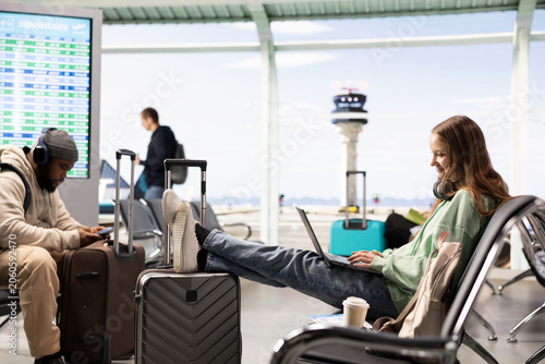 Fotografie Professional girl digital nomad uses laptop in a crowded airport lounge, demonstrating the work anywhere concept, Nomadic lifestyle of remote worker enjoys global mobility and flexible career