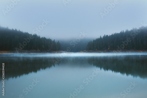 g over calm lake surrounded by forest