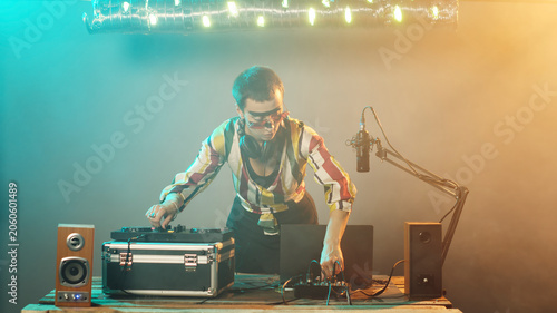 Fotografie Woman artist mixing techno sounds with turntables equipment, modern musician playing disco tunes and remix at stereo electronic mixer