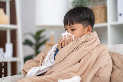 Obraz na płótnie Young asian boy sneezing or blowing his nose and mouth with tissue, cold allergi