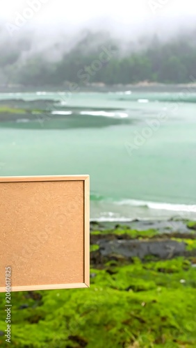 Blank wooden frame mockup set against a scenic misty river landscape with green mossy banks.