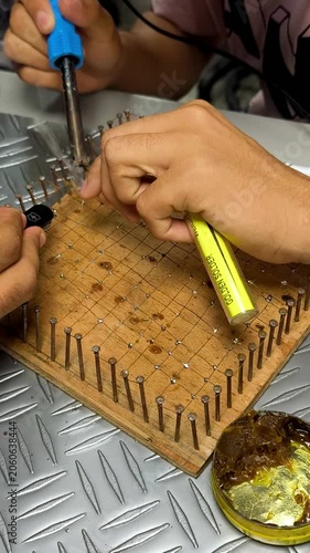 Close-up of hands working with soldering tools on an electronic training board, representing electronics education, engineering skills, technology repair and technical craftsmanship.