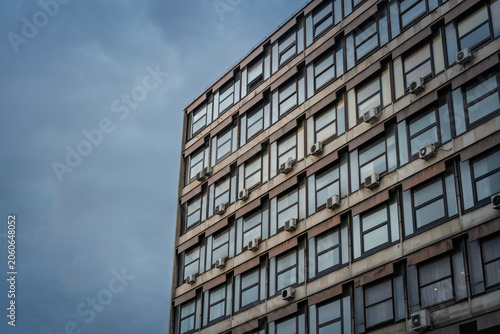 Obraz na plátně Brutalist office building in Belgrade in Serbia with concrete facade, grid windows, exterior air conditioners and stormy sky, reflecting communist era urban architecture and city offices