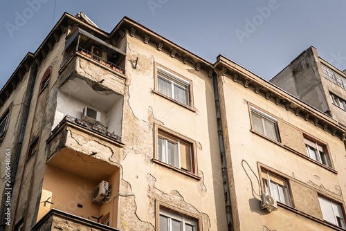 Decaying residential building facade in Stari Grad, Belgrade, Serbia with cracked plaster, worn balconies, apartment windows and signs of neglect in an older urban real estate and housing setting.