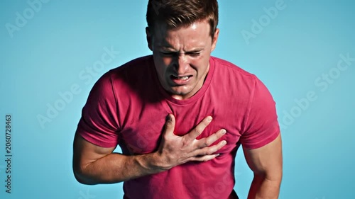 Man clutching chest in pain against blue background