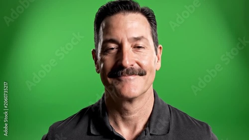 Man in black polo standing against green screen.