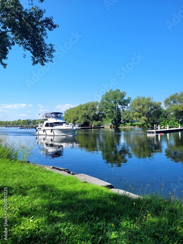 White luxury motor yacht cruising on a calm river with beautiful water reflection on a sunny summer day