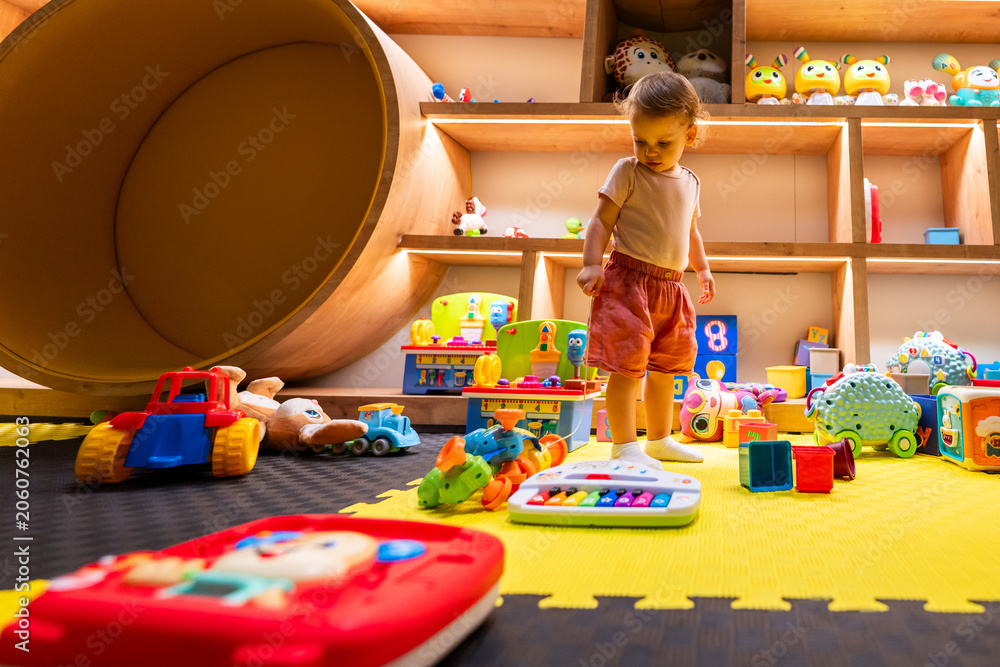 Fototapeta premium Toddler surrounded by colorful toys in an engaging indoor playroom designed for fun, learning, and creative exploration