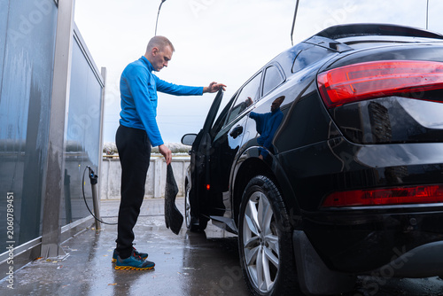 Fotografie Man cleans his vehicle at self service car wash station cleaning removable car mats