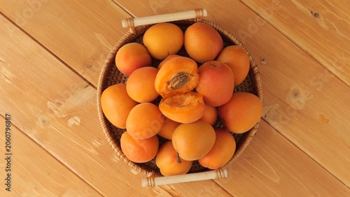 Ripe apricots in a basket rotating on a wooden table