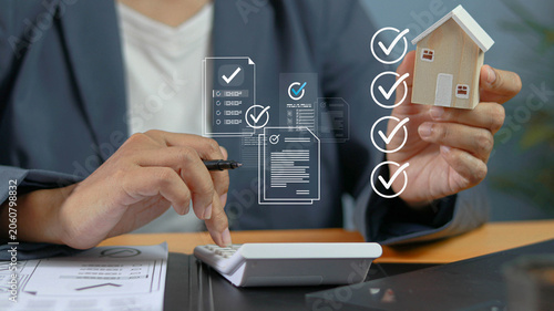 Foto Real estate professional reviewing property compliance checklist and housing documents while calculating investment costs