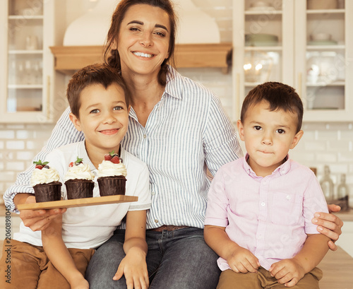 Mom and two little boys, brothers, are eating homemade cupcakes.