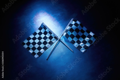 Two checkered flags cross on a dark, spotlighted surface