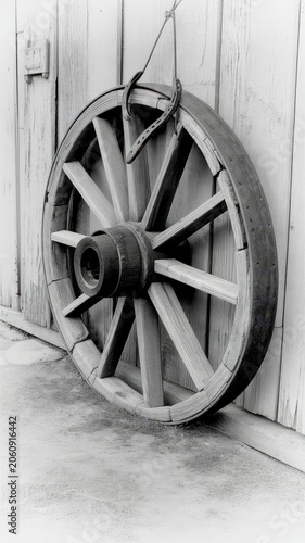 Old wooden wagon wheel leaning against a rustic weathered vertical plank wall