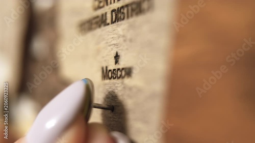 Female hand placing pin with Ukrainian flag on Moscow on map. Ukrainian Russian war