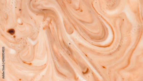 The abstract background is a swirl of chocolate and milk cream, creating a warm, marbled liquid texture