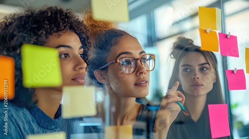 Professional colleagues analyze strategic notes on a glass board while working together in a bright corporate office environment.
